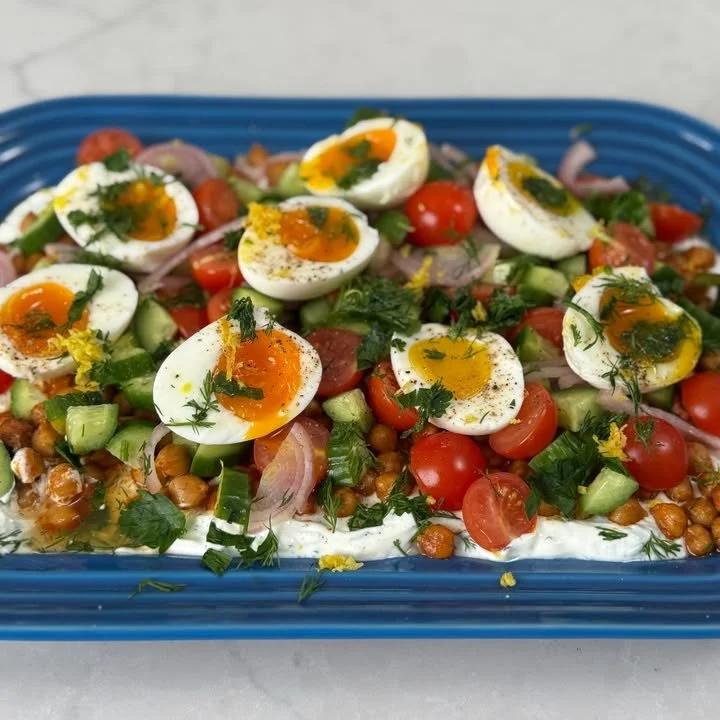 Plate of spiced chickpeas and eggs garnished with herbs.