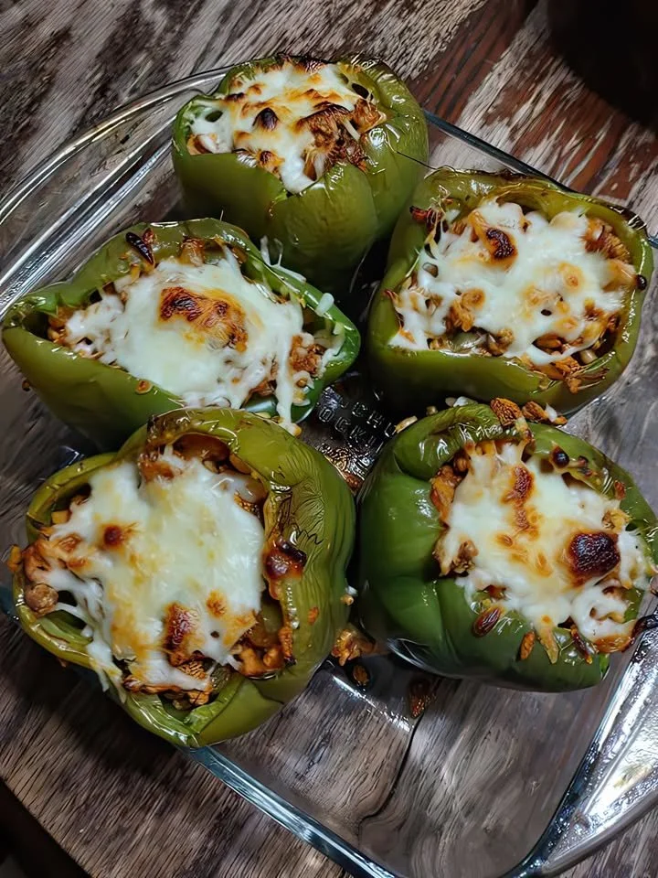 Stuffed bell peppers with rice, meat, and cheese on a wooden table