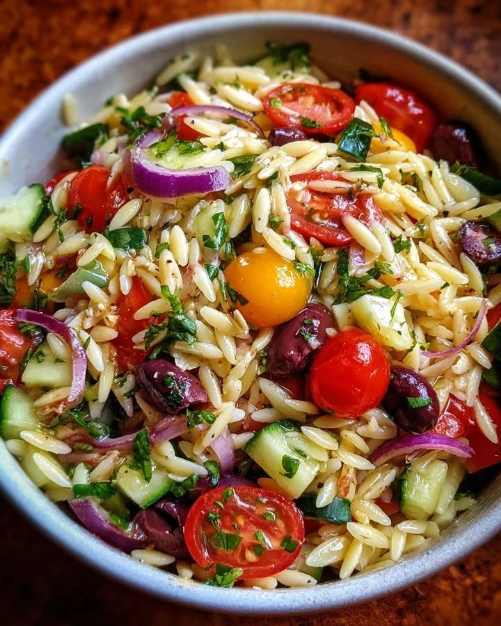 A colorful bowl of Summer Orzo Salad with fresh vegetables and herbs