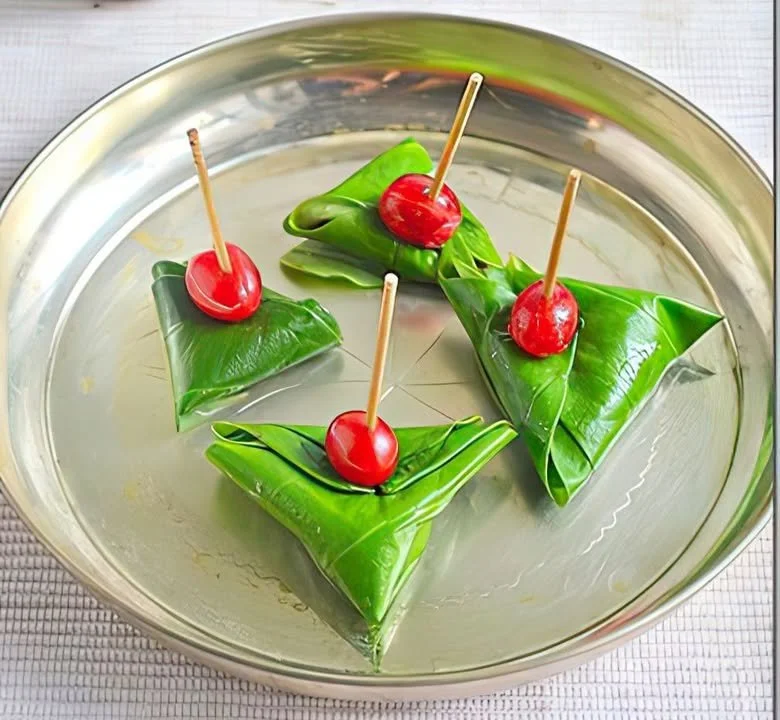 Plate of sweet betel leaf (sweet pan) with colorful fillings wrapped for serving.