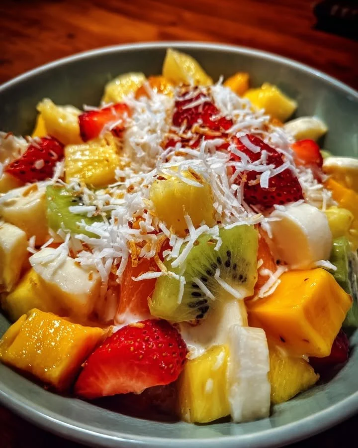 Colorful tropical fruit salad with coconut lime dressing served in a bowl.