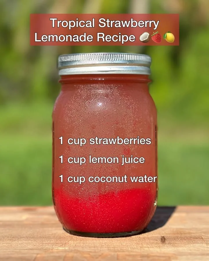 Glass of tropical strawberry lemonade garnished with fresh strawberries and mint leaves