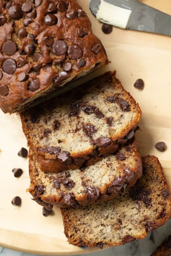 Freshly baked banana bread with nuts and chocolate chips on a wooden table