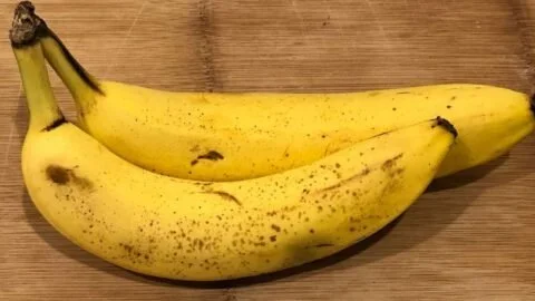 A loaf of homemade banana bread with slices cut and displayed on a wooden table.