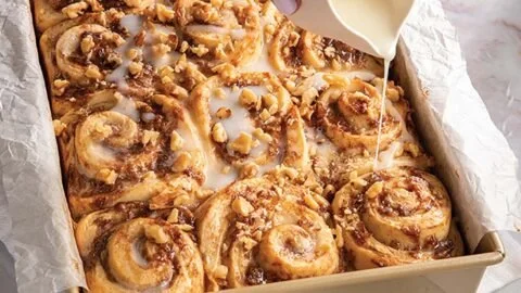 Delicious banana bread sweet rolls drizzled with icing on a rustic wooden table