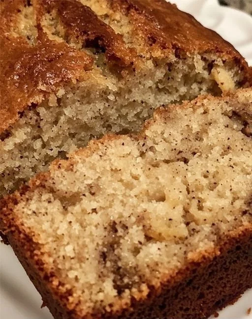 Freshly baked classic moist banana bread loaf on a wooden cutting board.