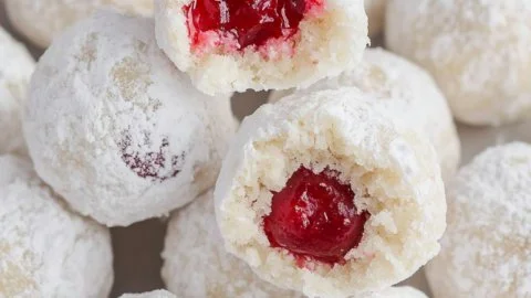 Delicious Cherry Snowball Cookies dusted with powdered sugar on a plate.