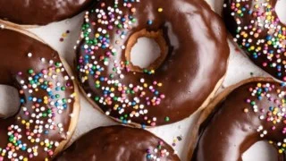 Freshly baked chocolate-glazed donuts on a colorful plate.