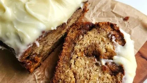 Cinnamon Roll Banana Bread sliced on a wooden board with a cinnamon swirl