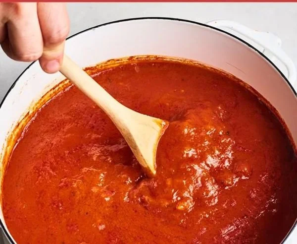 A bowl of classic marinara sauce with fresh herbs and tomatoes.