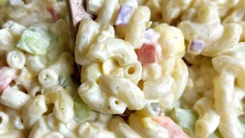Bowl of creamy macaroni salad with vegetables garnished on top