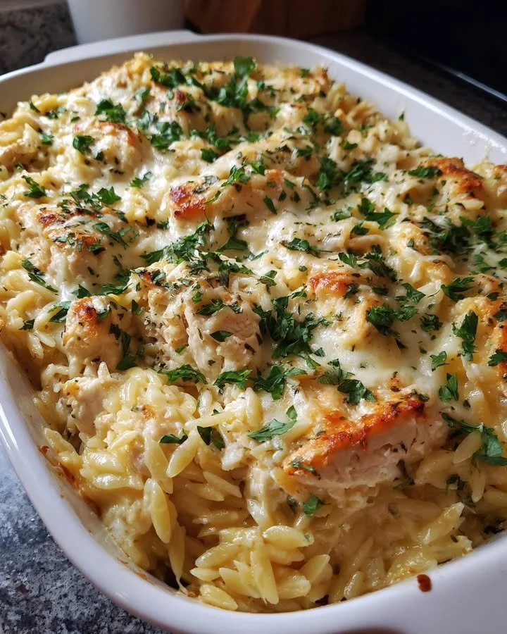 Creamy Ricotta Chicken Orzo Bake with fresh herbs and chicken in a casserole dish.