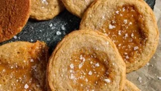 Crispy salted caramel cookies on a plate, garnished with sea salt.