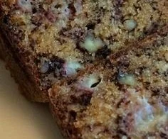 Slice of extreme banana nut bread with nuts and banana slices on a wooden board