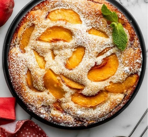 Fresh peach cake with slices of ripe peaches and whipped cream topping