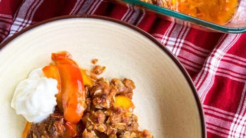 Fresh peach crisp dessert topped with oats and sugar, served in a rustic dish