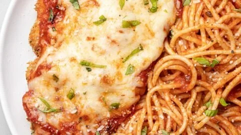 Healthy chicken parmesan dish garnished with fresh herbs and served on a plate