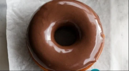 Homemade glazed chocolate donuts on a plate with sprinkles