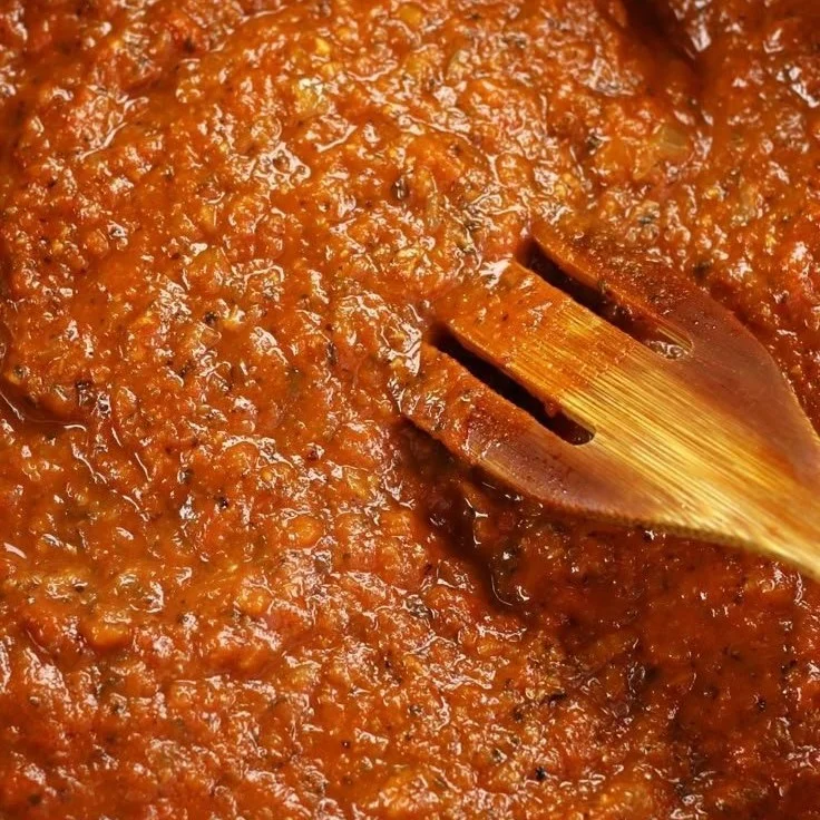 A bowl of homemade marinara sauce with fresh herbs and tomatoes