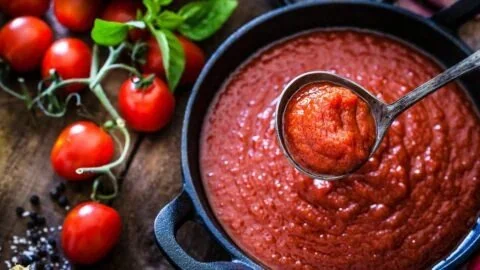Bowl of homemade marinara sauce with fresh herbs and tomatoes