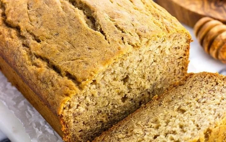 Loaf of honey banana bread with slices cut on a wooden board