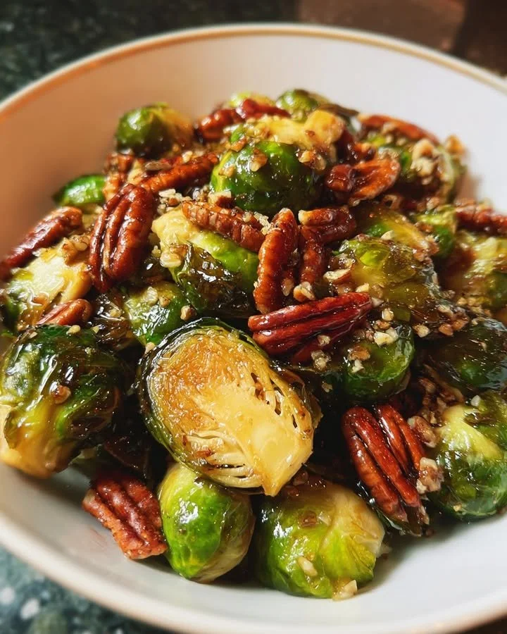 Honey-glazed Brussels sprouts topped with toasted pecans in a serving dish.