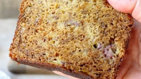 Slice of irresistibly moist banana bread on a wooden cutting board