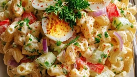 Delicious homemade macaroni salad served in a bowl with fresh vegetables