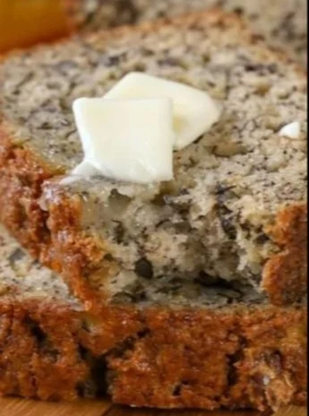 Slice of moist banana bread on a wooden cutting board