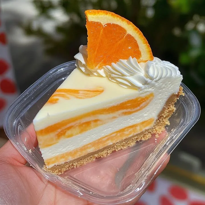 Slice of creamy orange creamsicle cheesecake with a vibrant orange garnish