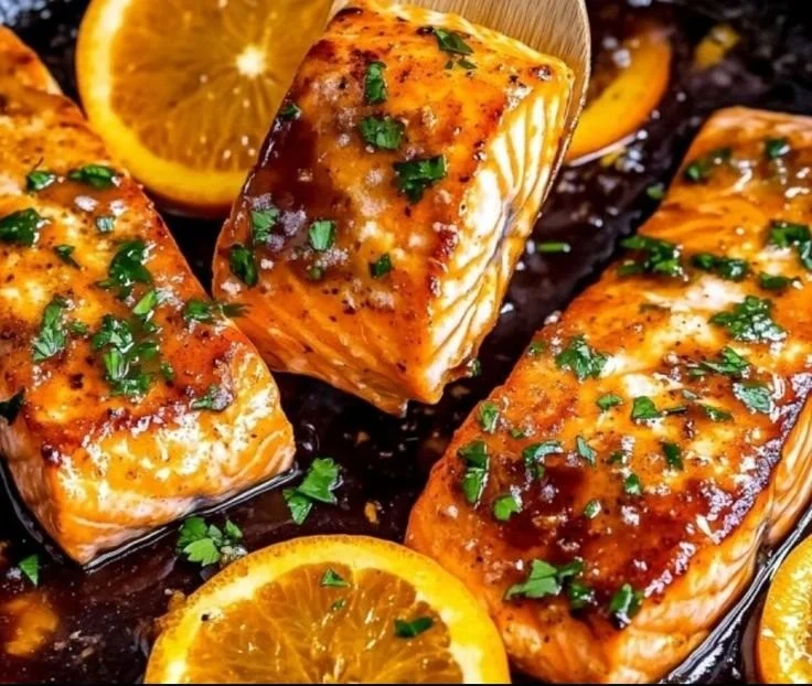 Baked orange glazed salmon garnished with herbs and citrus slices