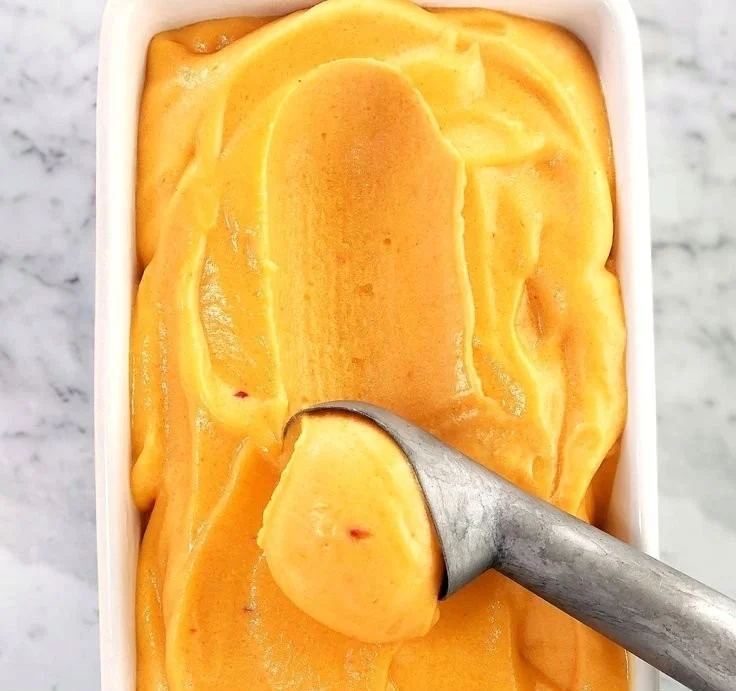 Delicious homemade Peach Sorbet served in a bowl with fresh peaches