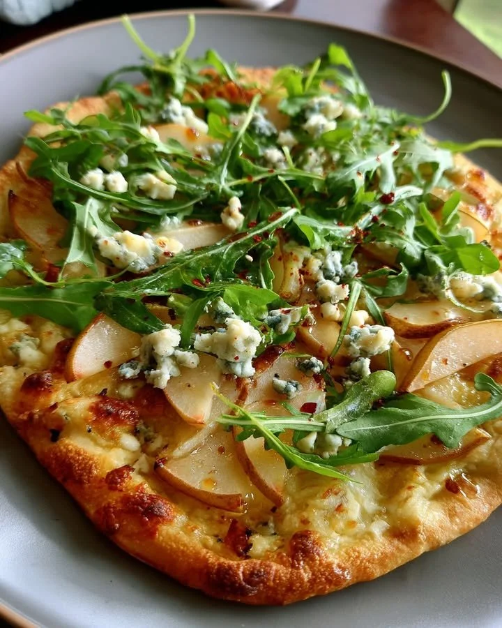Pear and blue cheese flatbread topped with arugula and hot honey