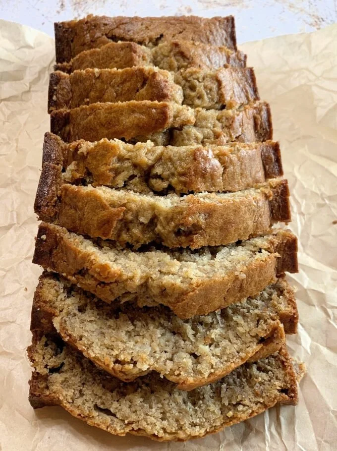 Slice of perfect banana nut bread on a wooden cutting board