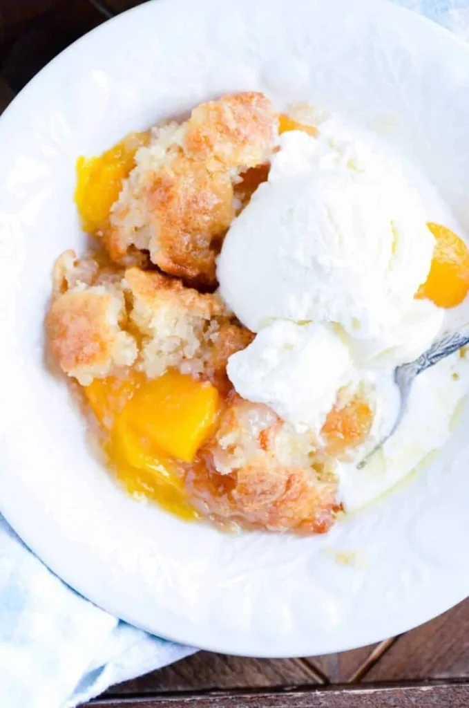 Delicious homemade peach cobbler served in a dish with a scoop of ice cream
