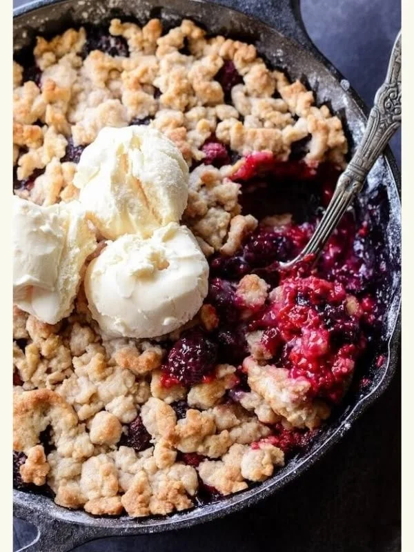 Delicious skillet berry cobbler topped with crispy crust and fresh berries