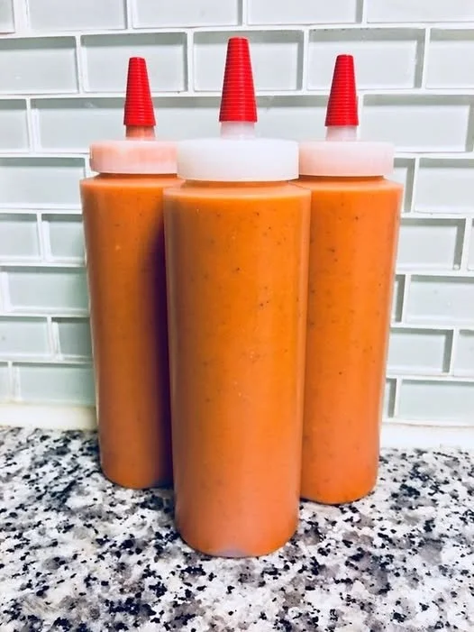 Smoked habanero sauce in a glass jar with fresh peppers.