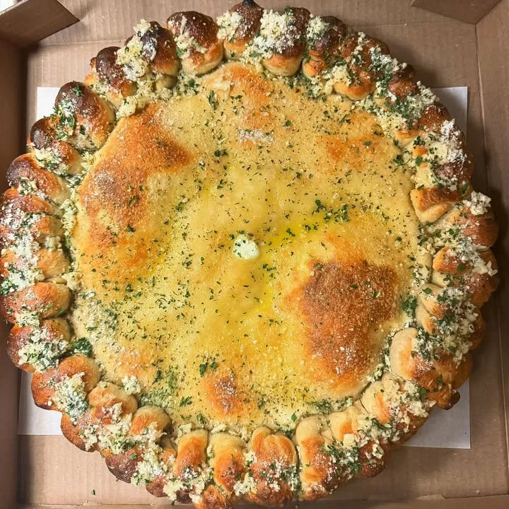 Stuffed calzone pizza with garlic knot crust on a wooden table