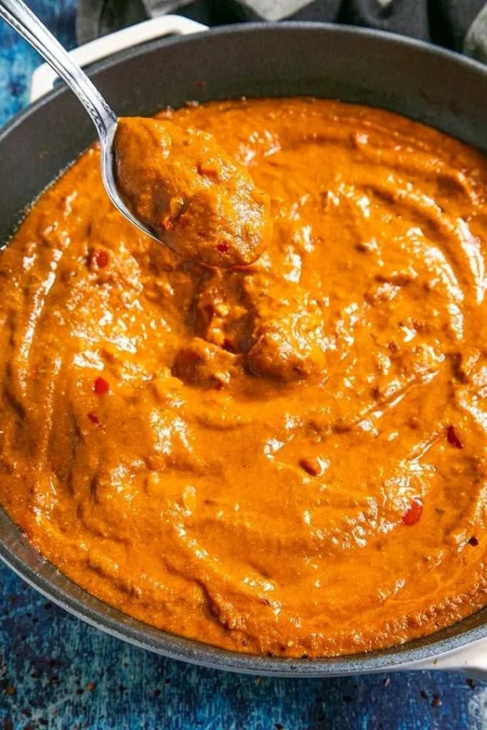 Delicious Tikka Masala Sauce in a bowl with spices and herbs around it.