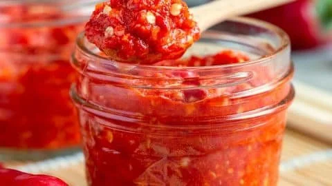 Bowl of Asian Chili Garlic Sauce with fresh garlic and chili peppers.