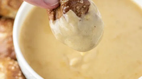Creamy Beer Cheese Dip served with pretzels on a wooden board