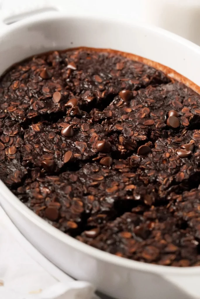 Chocolate brownie baked oatmeal in a bowl topped with fruits and nuts