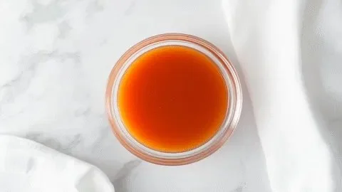 Homemade Buffalo Chicken Wing Sauce in a glass bowl with wings