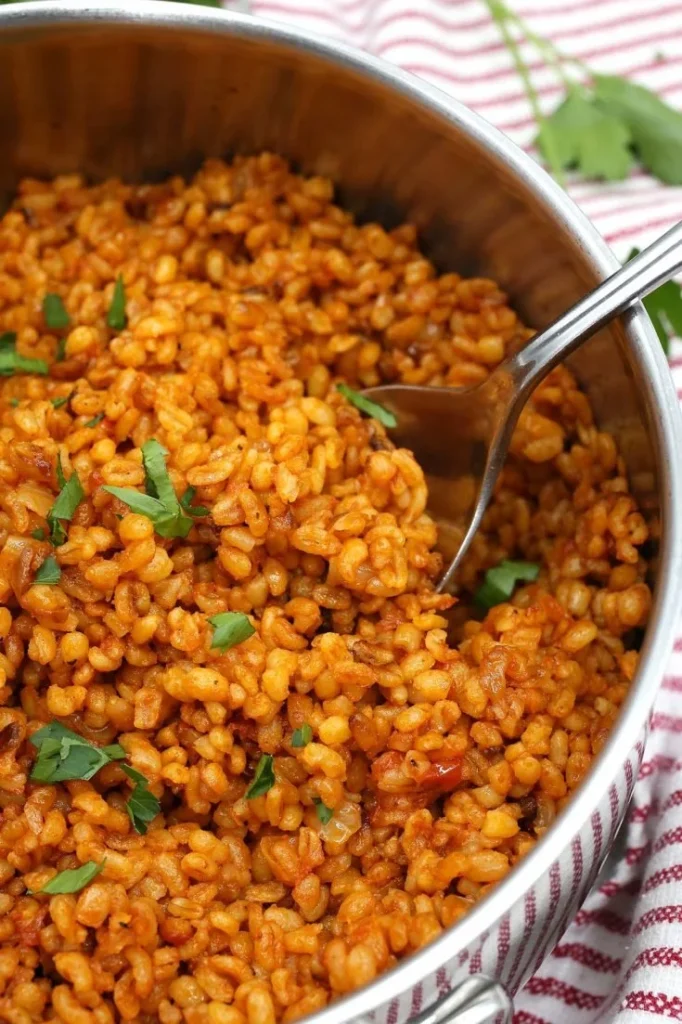 Bulgur Tomato Pilaf served in a bowl with fresh herbs and tomatoes