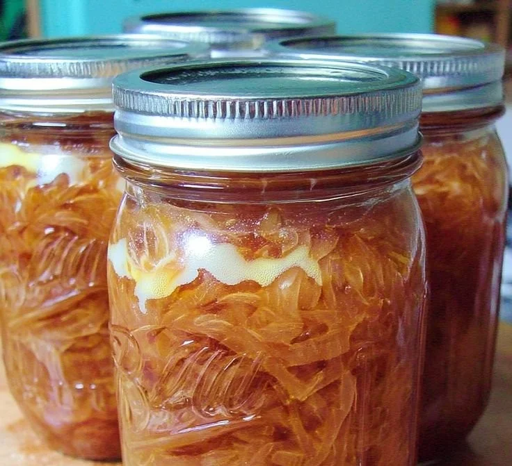 Jars of canned caramelized onions on a kitchen counter.