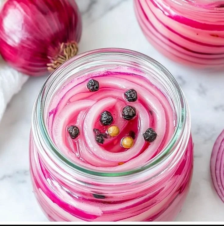 Homemade pickled red onions in a jar, vibrant color and tangy flavor.
