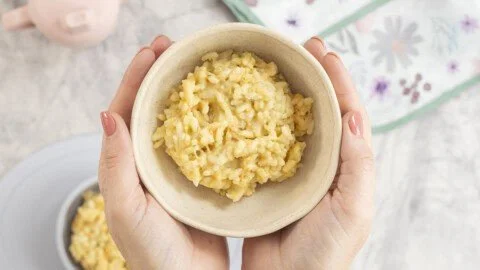 Bowl of easy cheesy rice with melted cheese and herbs