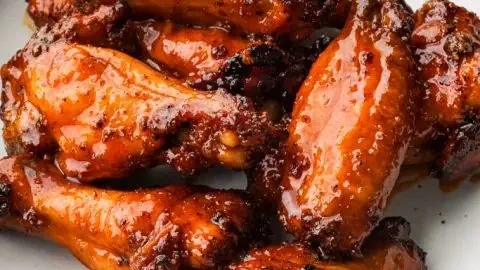 Plate of easy honey hot wings garnished with herbs and served with dipping sauce.