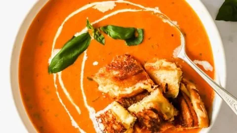 Bowl of easy roasted tomato soup garnished with fresh herbs