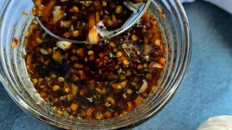 Bowl of Garlic Honey Soy Sauce with garlic cloves and honey drizzling on top